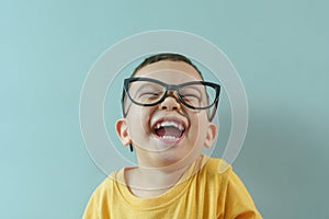 Asian boy in yellow shirt and eyeglasses laughing