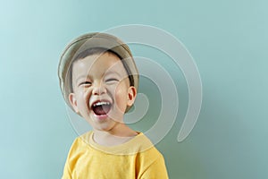 Asian boy in yellow shirt and hat laughing
