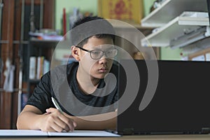 Asian boys sitting and studying in front of a laptop computer.