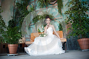 Asian bride with flowers in white dress sitting on sofa