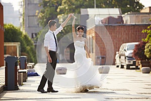 Asian bride and groom dancing in parking lot