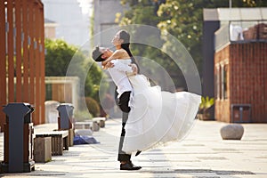 Asian bride and groom hugging outdoors