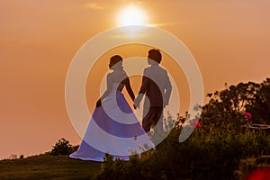 Asian Bride and Groom Standing on Mountain at Sunset