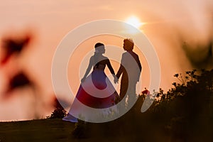 Asian Bride and Groom Standing on Mountain at Sunset