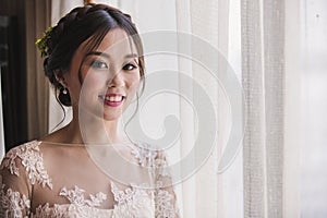 Asian bride standing near window in dressing room