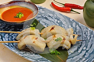 Asian brochette of calamari grilled with sauce on a banana leaf