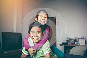 Asian brother with his sister on piggyback ride and smiling happily.