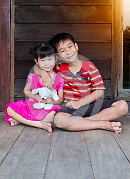 Asian brother put one`s arm around sister`s shoulder and smiling