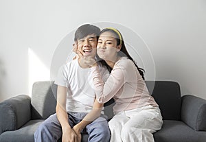 Asian brother and sister hugging with care and love sit on sofa.