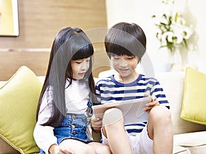 Asian brother and sister using digital tablet