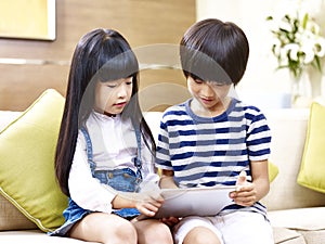 Asian brother and sister using digital tablet at home