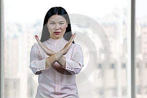 Asian brunette woman holding two arms crossed gesturing no sign.