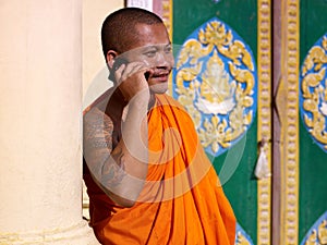 Asian buddhist monk talking on phone in temple