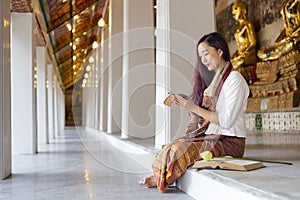 Asian buddhist woman is reading Sanskrit ancient palm leaf manuscript of Tripitaka the Lord Buddha dhamma teaching while sitting
