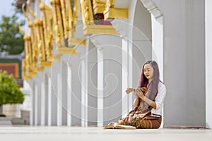 Asian buddhist woman is reading Sanskrit ancient palm leaf manuscript of Tripitaka the Lord Buddha dhamma teaching while sitting