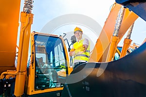 Asian builder in excavator on construction site