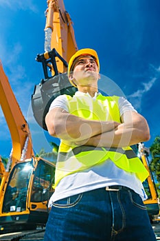 Asian builder in front of shovel excavator