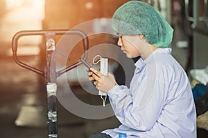 Asian Burmese young woman labor worker sit and relax, playing cell phones, waiting for work shifts in food hygiene factory