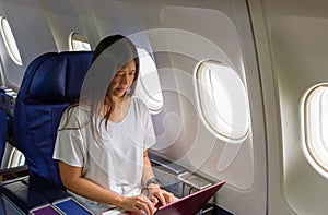 Asian businees woman comercial plane passenger using laptop on board for working while sitting in airplane. Traveling and