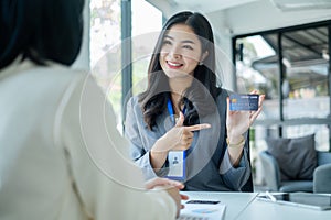 Asian business customer service representatives work and smile serve sell credit card to customers. choosing insurance plan in