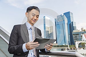 Asian business male using portable computer on city