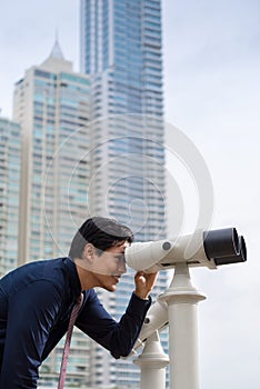 Asian business man with binoculars looking at city