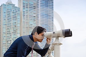 Asian business man with binoculars looking at city