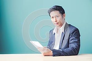 Asian business man using digital tablet while sitting at office