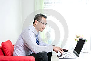 Asian business man using laptop computer with happiness