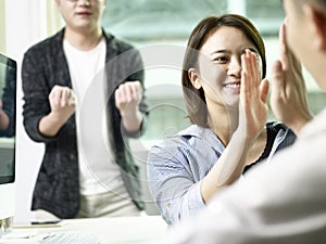 Asian business people celebrating success in office