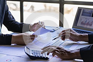 Asian business people meeting with laptop and graph papers to analyze and discuss situation on financial report