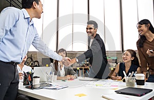 Asian business people smart casual wear shaking hands while working in the creative office. Business team creative concept.
