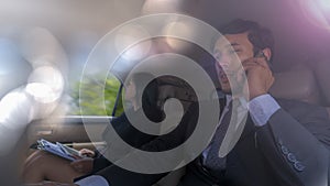 Asian business people smart man talking with smartphone and sitting near secretary businesswoman in back seat during car driving.