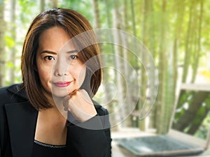 Asian business woman with blur green garden background. Smiling