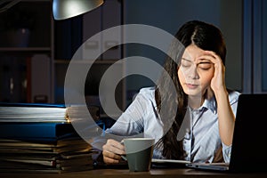 Asian business woman drink coffee headache overtime working late