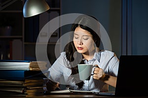 Asian business woman drink coffee working overtime late night