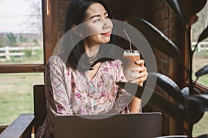 Asian business woman drinking coffee and working on computer laptop at cafe shop,  work from anywhere concept