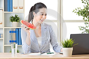 Asian business woman having fresh watermelon and using computer