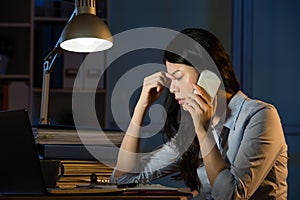 Asian business woman headache on smartphone working overtime