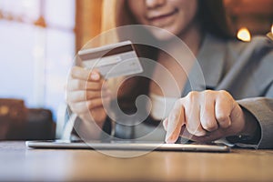 Asian business woman holding credit card while using tablet