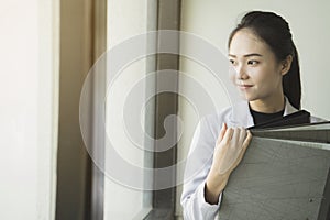 Asian Business woman holding document files beside a window