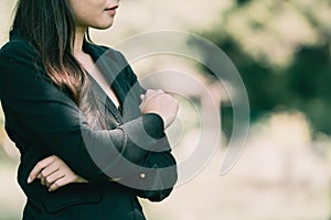 Asian business woman with long hair In a black suit standing hold her hands in the park