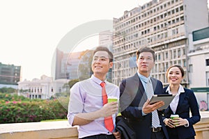 Asian business woman and men working outside on tablet computer