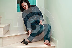 Asian business woman pain ankle, foot with leg cramp and fall down the stairs because slippery surfaces in office