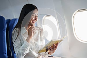 Asian business woman passenger sitting on business class luxury plane while working using notebook book while travel