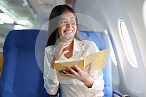 Asian business woman passenger sitting on business class luxury plane while working using notebook book while travel