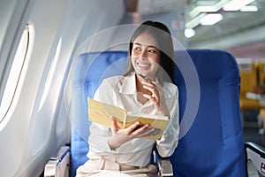 Asian business woman passenger sitting on business class luxury plane while working using notebook book while travel
