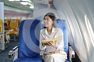 Asian business woman passenger sitting on business class luxury plane while working using notebook book while travel