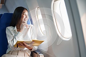 Asian business woman passenger sitting on business class luxury plane while working using notebook book while travel
