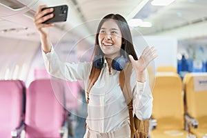 Asian business woman passenger sitting on business class luxury plane while working using smart phone mobile talking or